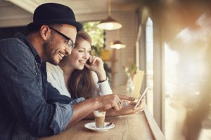 Smiling young couple in a coffee shop using touch screen computer. Young man and woman in a restaurant looking at digital tablet.